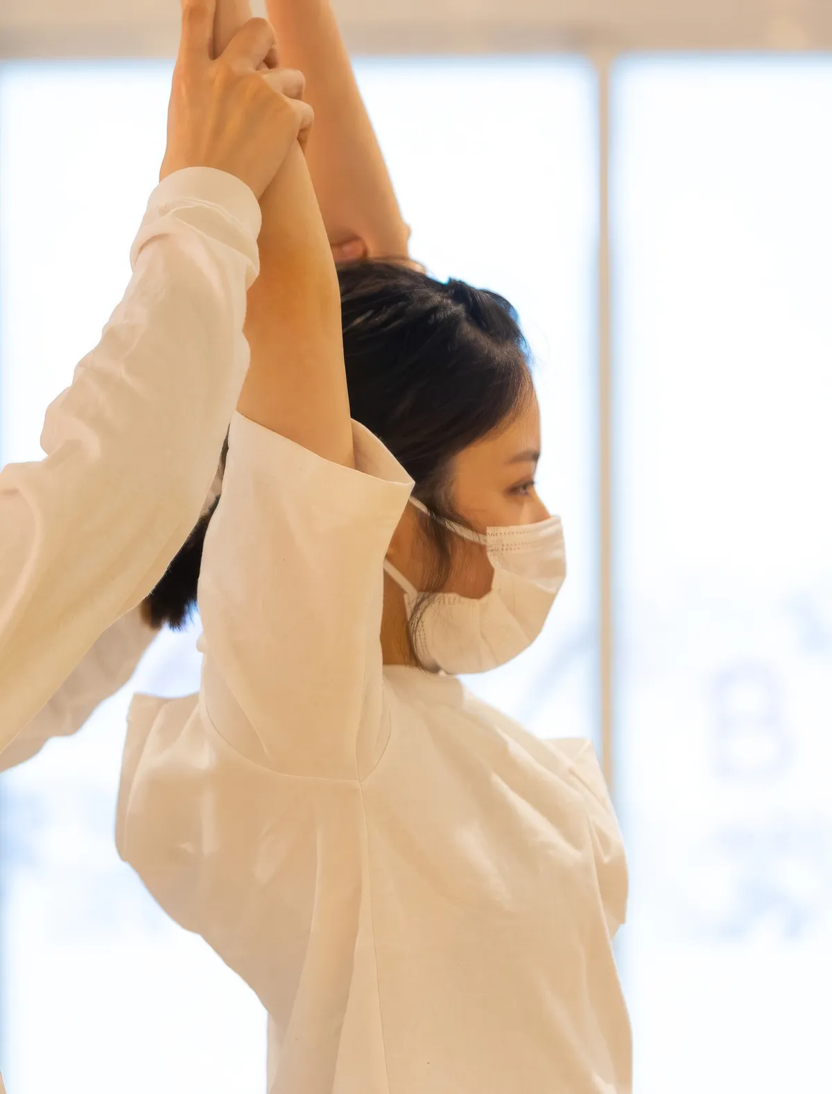 窓辺の自然光のなかでストレッチをする女性